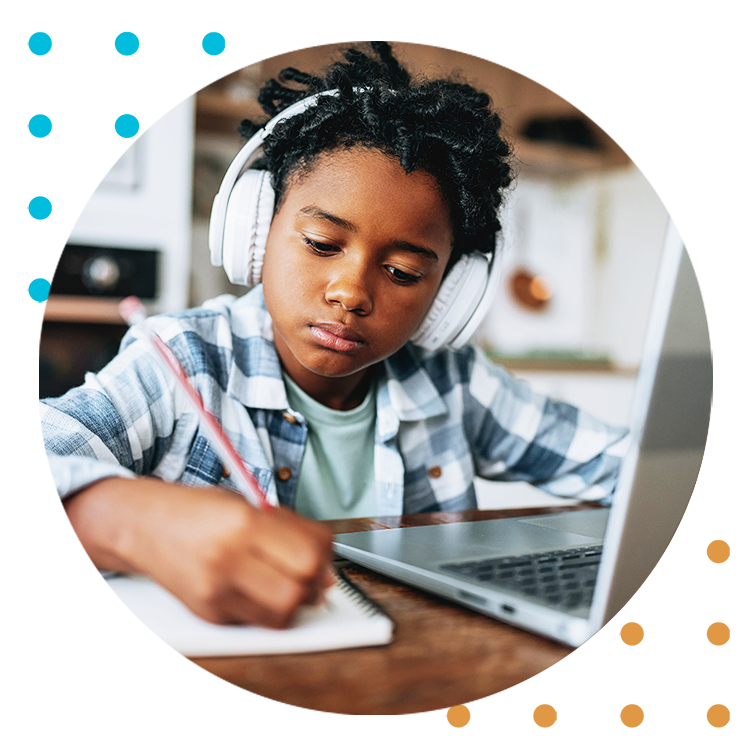 A young boy wears headphones while working on school work.