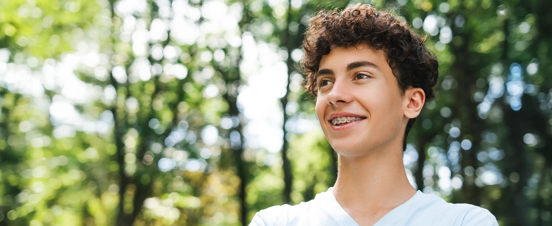 A teenage boy with braces is smiling.